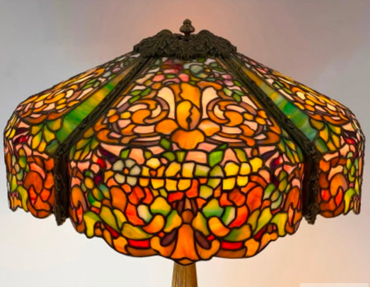 Colorful stained glass lampshade with intricate design on a plain background