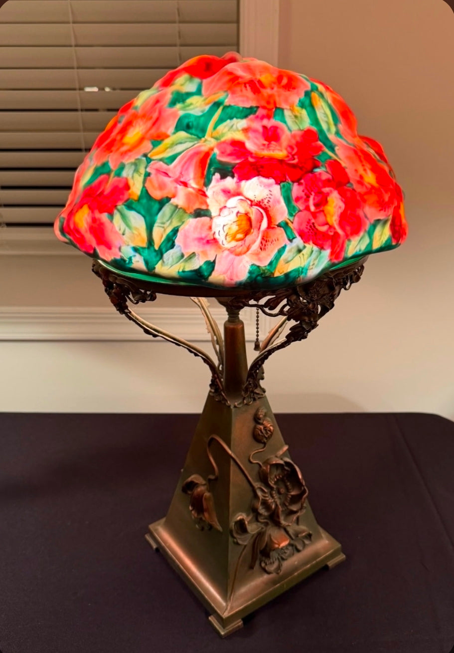 Decorative lamp with floral glass shade on a dark surface