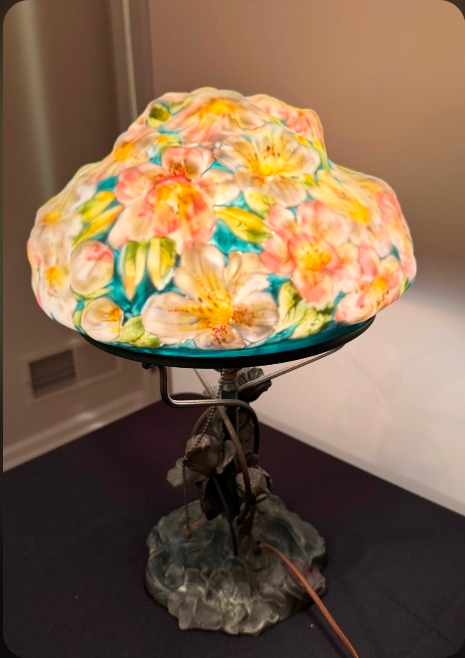 Floral-patterned lamp with a colorful glass shade on a dark surface.